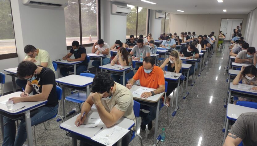 Sala com diversas cadeiras ocupadas por inscritos realizando prova de residência médica no HCN