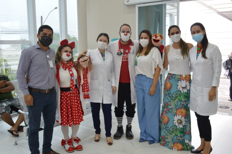 Equipe e colaboradores do Hetrin posam para uma foto lado a lado, com o grupo voluntário Missão Sorrisos que são palhaços com fantoches.