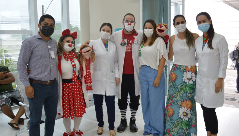 Equipe e colaboradores do Hetrin posam para uma foto lado a lado, com o grupo voluntário Missão Sorrisos que são palhaços com fantoches.