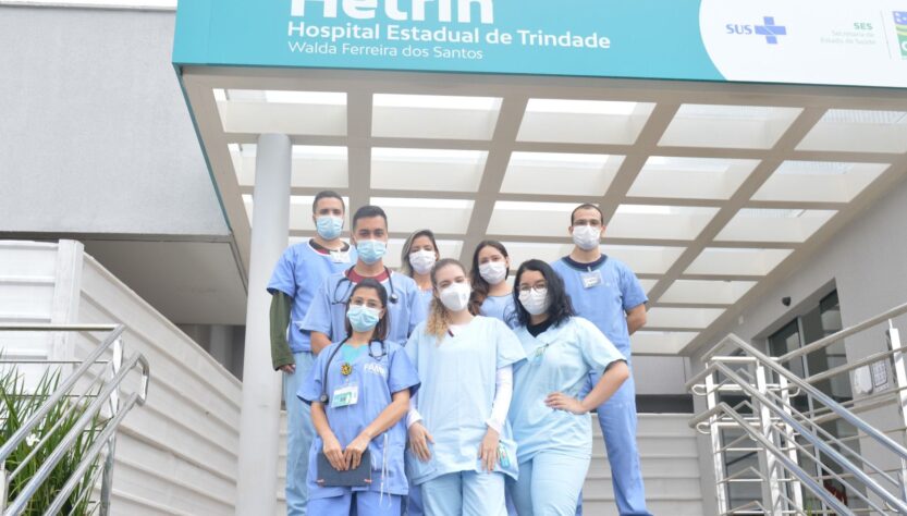 Alunos de medicina, entre meninas e meninos estão à frente do hospital Hetrin nas escadas com roupas no tom azul claro, todos participam do Programa de Estágio Hetrin