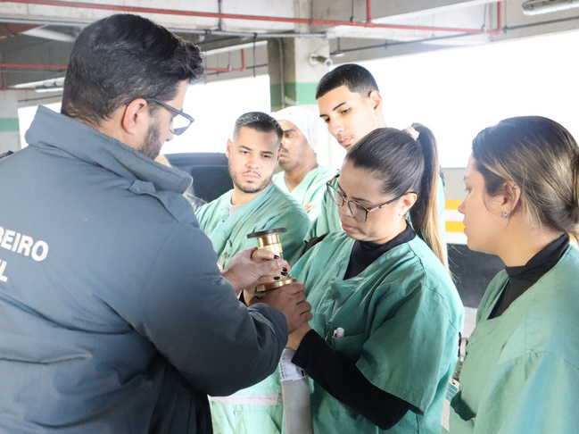 Imagem de colaboradores do Hospital Municipal da Brasilândia (HMB) durante o treinamento de brigada de incêndio, com atividades práticas de combate a princípios de fogo e primeiros socorros.